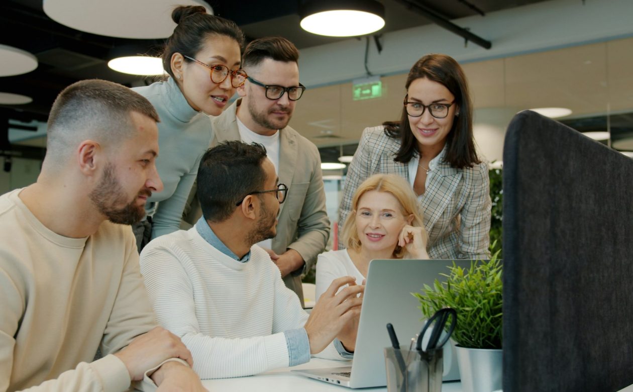 Equipe reunida analisando dados em laptop no escritório