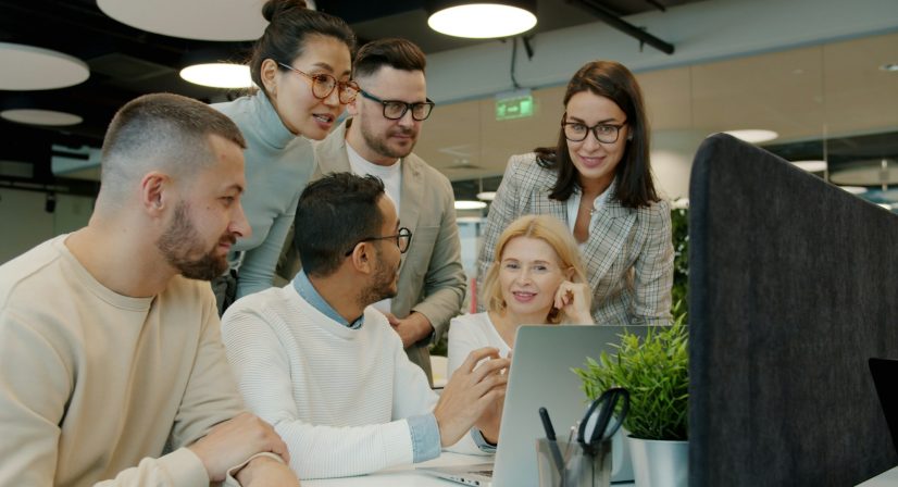 Equipe reunida analisando dados em laptop no escritório